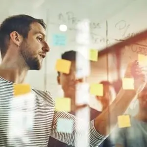 Group of people working with post-it notes photographed through glass wall.