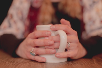 A woman's hands wrapped around a mug