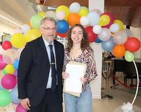 Man with woman holding certificate in front of balloon arch