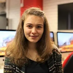 Young woman poses in a computer lab with multiple monitors behind her.