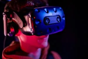 Person wears a blue virtual-reality headset under dramatic red and blue lighting.