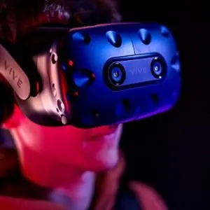 Person wears a blue virtual-reality headset under dramatic red and blue lighting.
