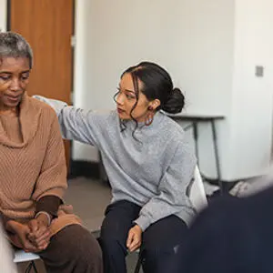 A young woman pictured comforting an older woman putting a hand on her shoulder