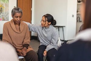 A young woman pictured comforting an older woman putting a hand on her shoulder