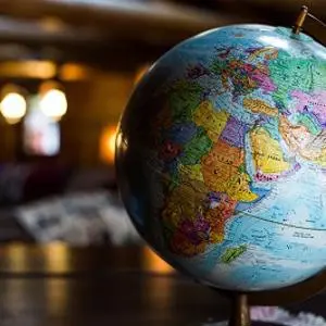 Colourful world globe stands on a table in a softly lit room.