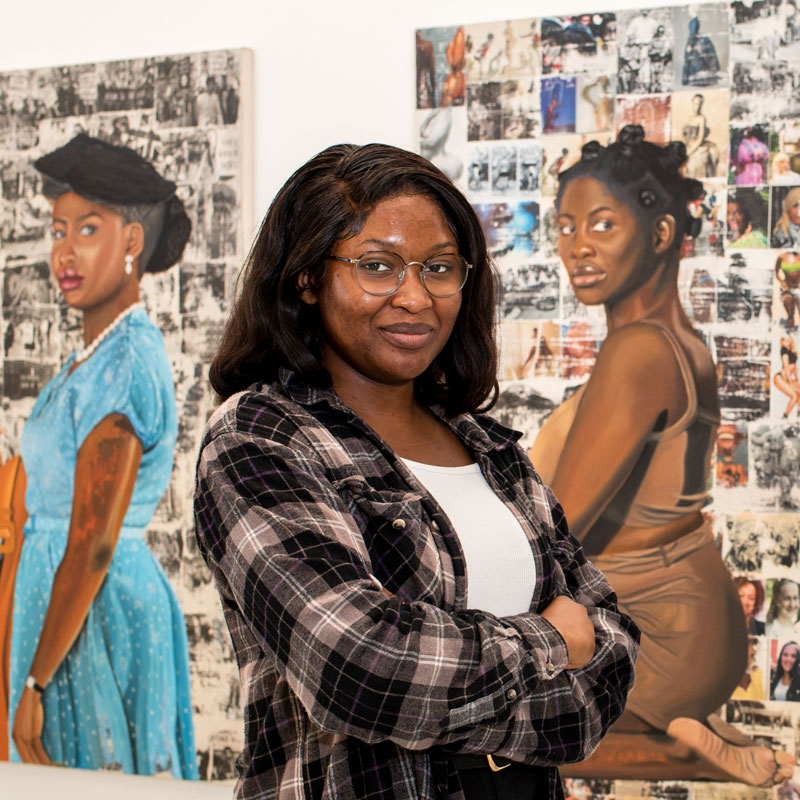 Fine Art student stands in front of two still life paintings