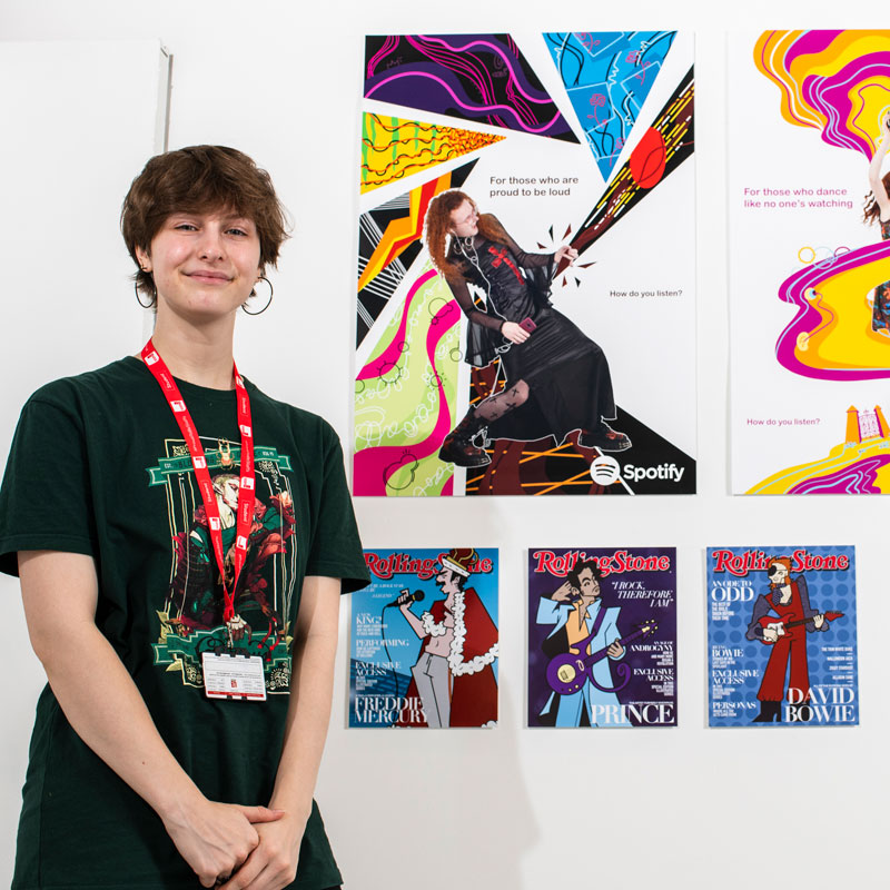 Illustration student with their designs for magazine covers at the Art and Design Showcase