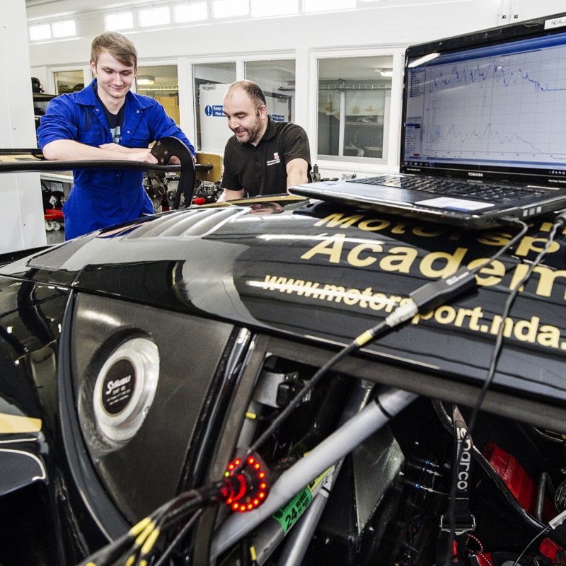 A male automotive student and lecturers discussing engine diagnostics