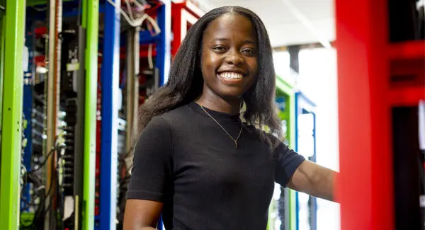A female with dark hair is smiling whilst in the networking lab
