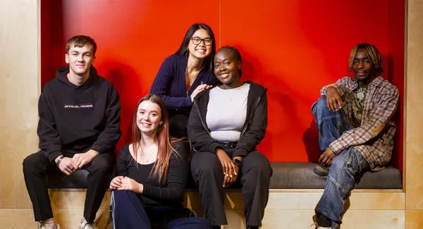 A group of diverse young students dressed in casual clothing, are hanging out together smiling