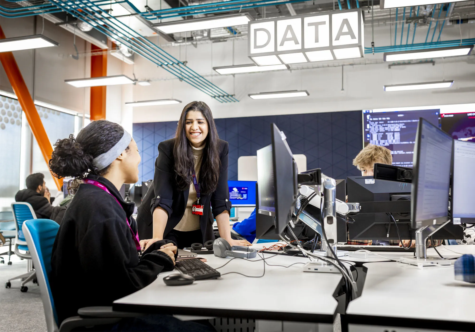 A female academic is chatting to a female student at her PC desk