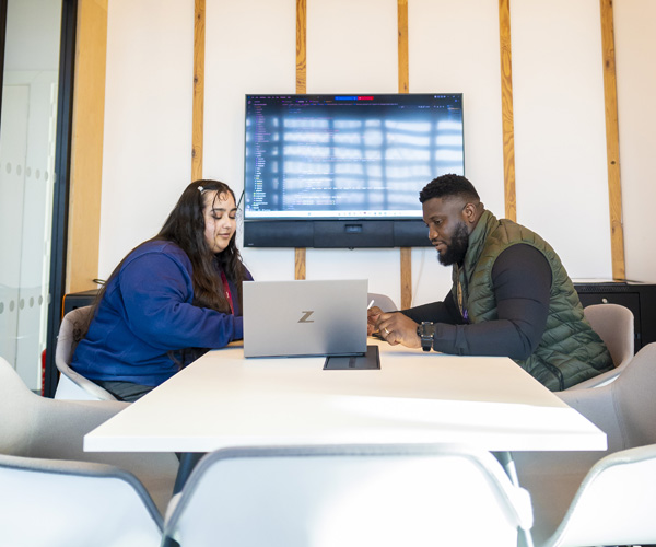 Two students are working together on a laptop