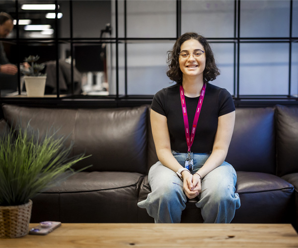 Female in casual clothing is sitting on a sofa