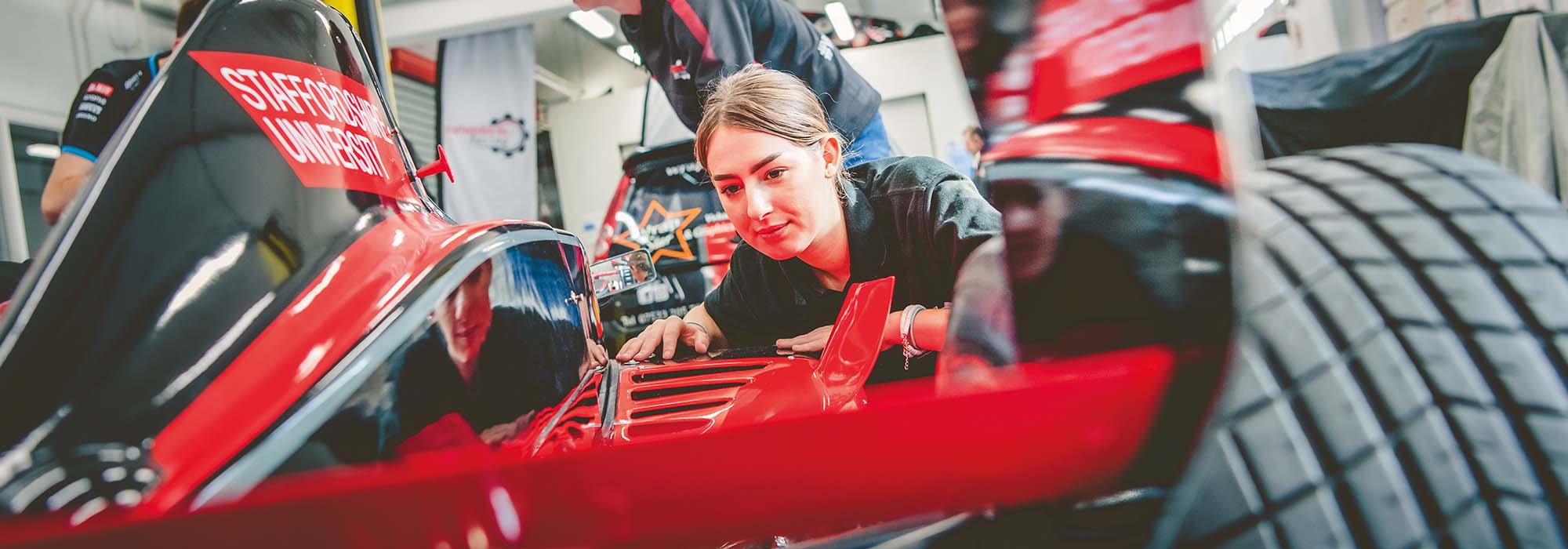female student working on a kit car in our engineering workshop