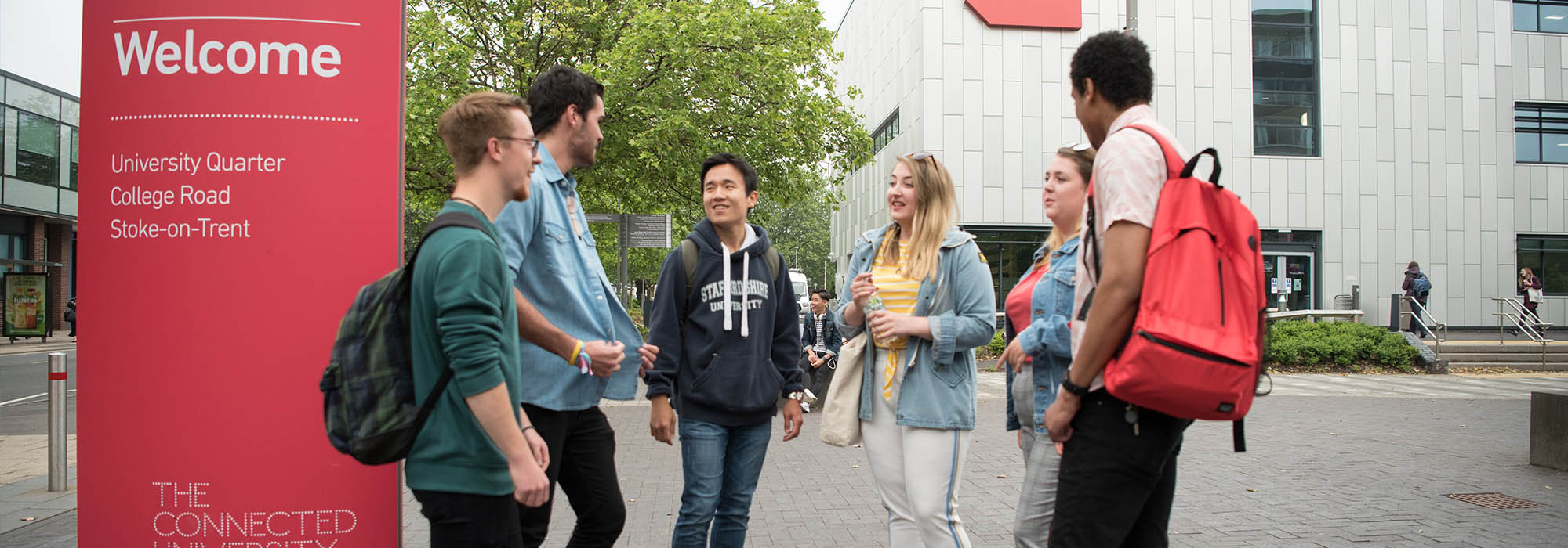 group of mixed students talking on the concourse on the College Road campus