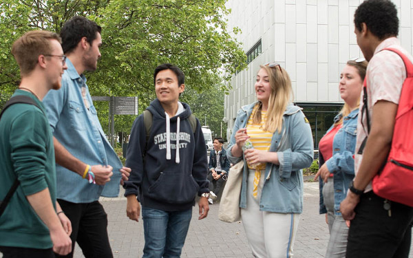 Mixed group of students chatting on the concourse outside the Beacon Building on Staffordshire University's Stoke-on-Trent campus.
