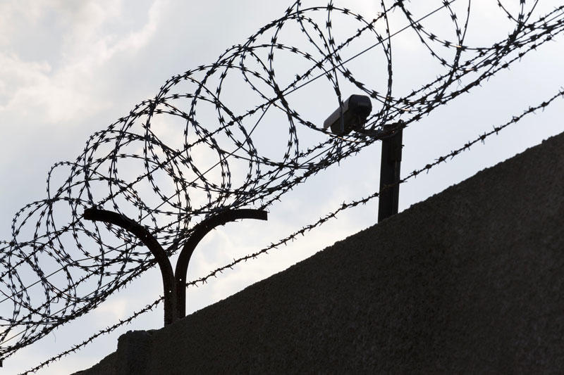 Picture showing wire round a prison wall in silhouette