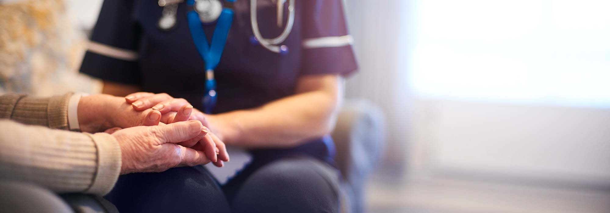 nurse holding the hand of an elderly patient