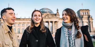 group of young people chatting and smiling in front of the Reichstag building in Berlin