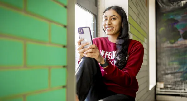 A female wearing a red sweater is using her phone