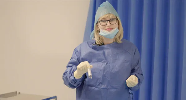 A female student with blonde hair is wearing blue scrubs uniform