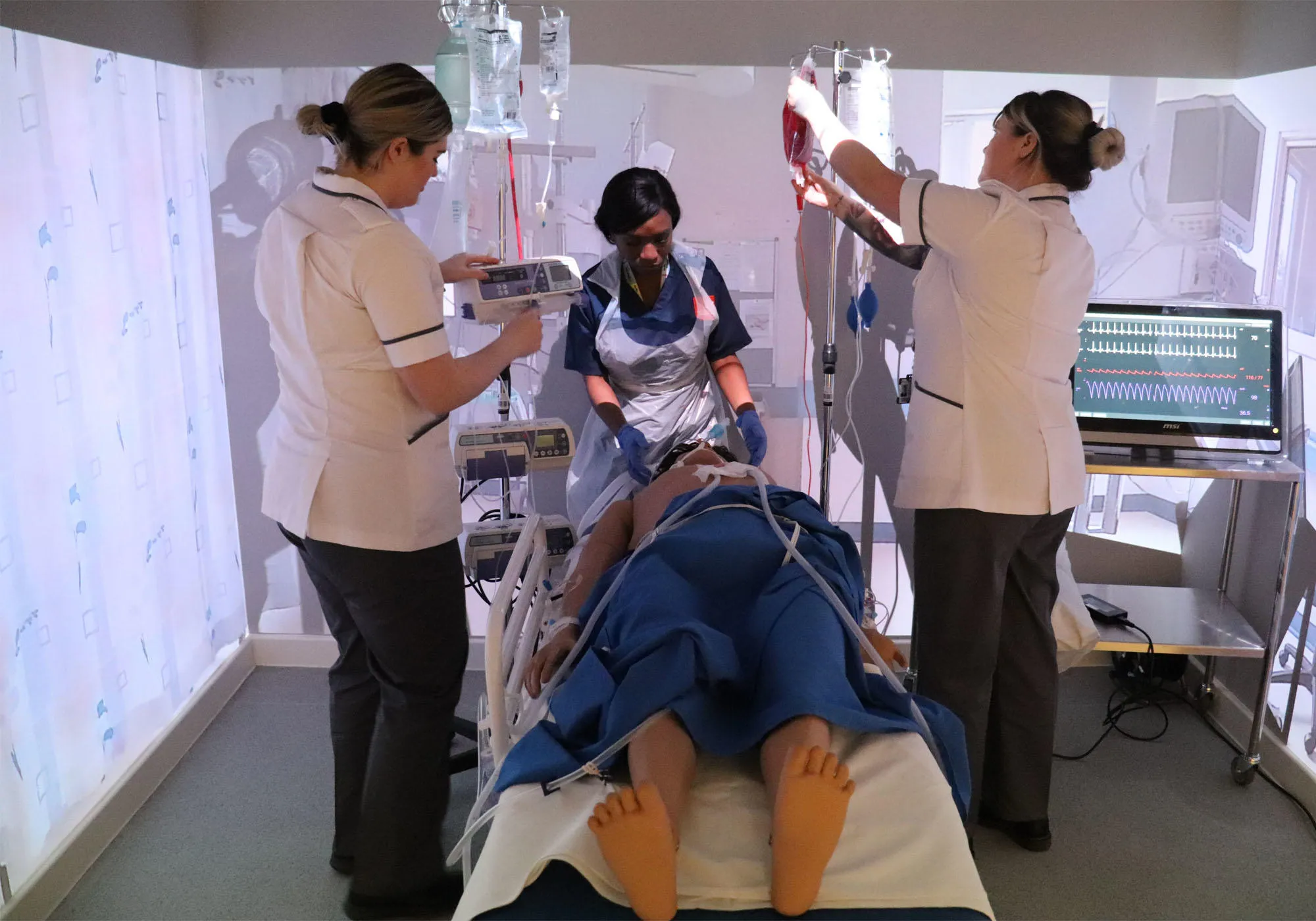 Healthcare students are working together on a dummy patient in a simmersive room
