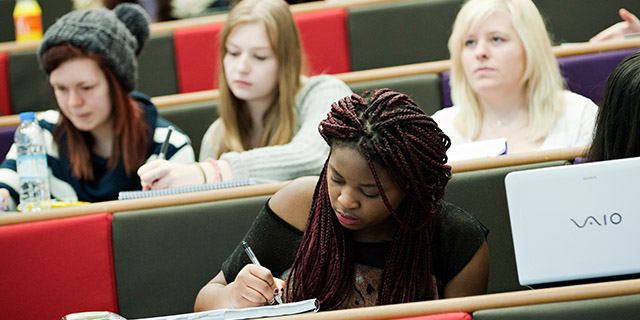 student taking notes in a lecture theatre