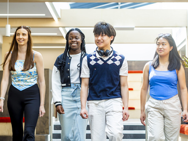 Casually dressed students are walking together inside an open modern breakout space