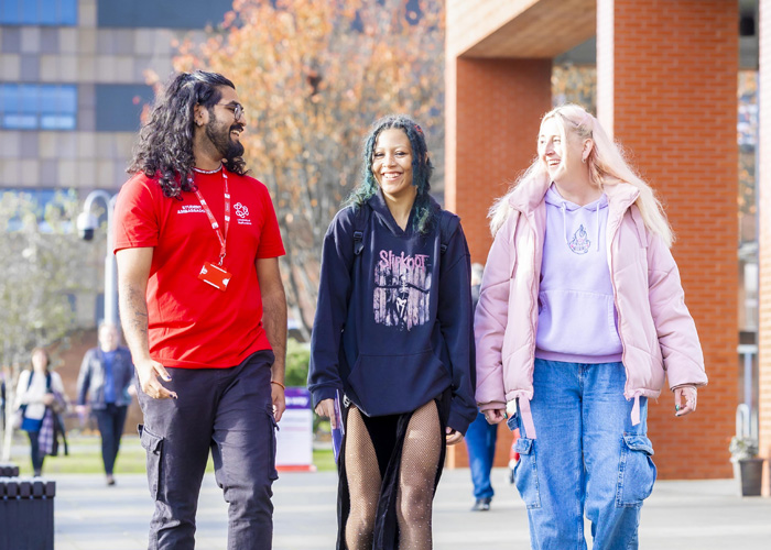 Two female visitors and a male student ambassador are walking around campus at an open day