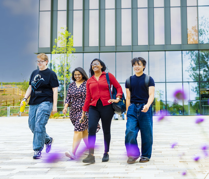 A group of students are walking together and smiling at the student village area