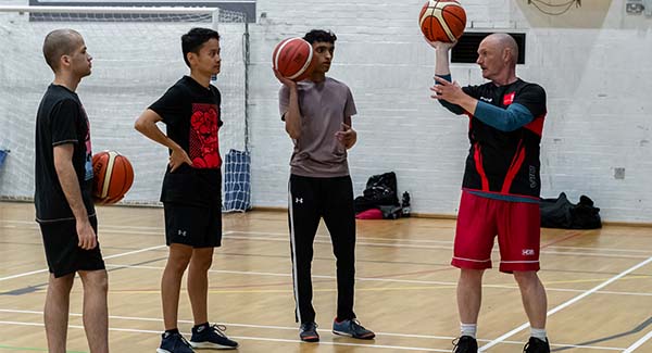 male coach teaches new students basketball skills