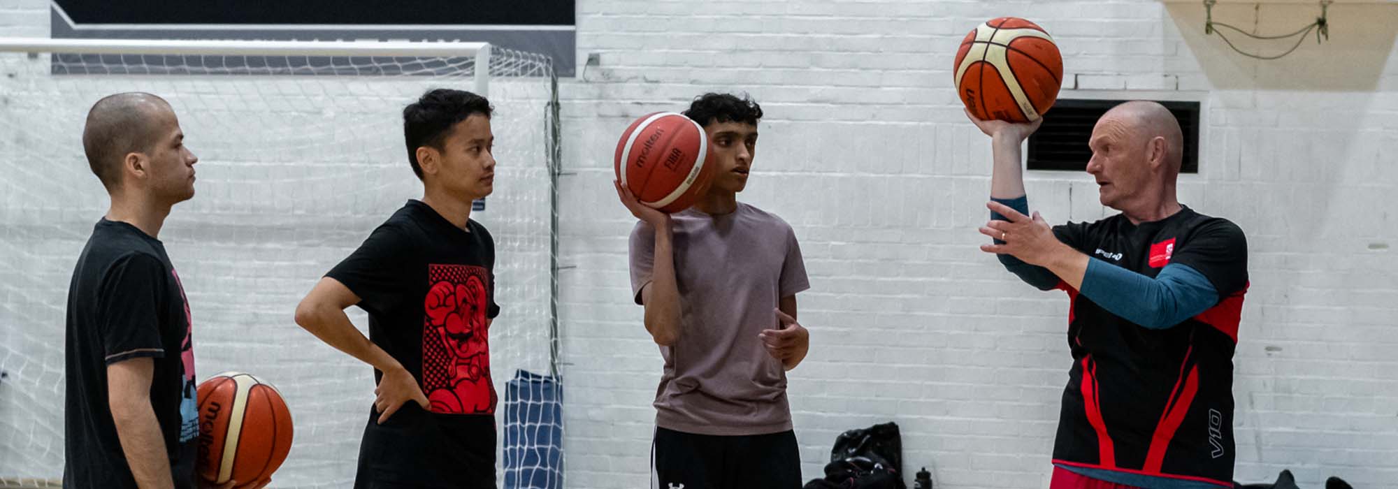 Male basketball coach teaches skills to students